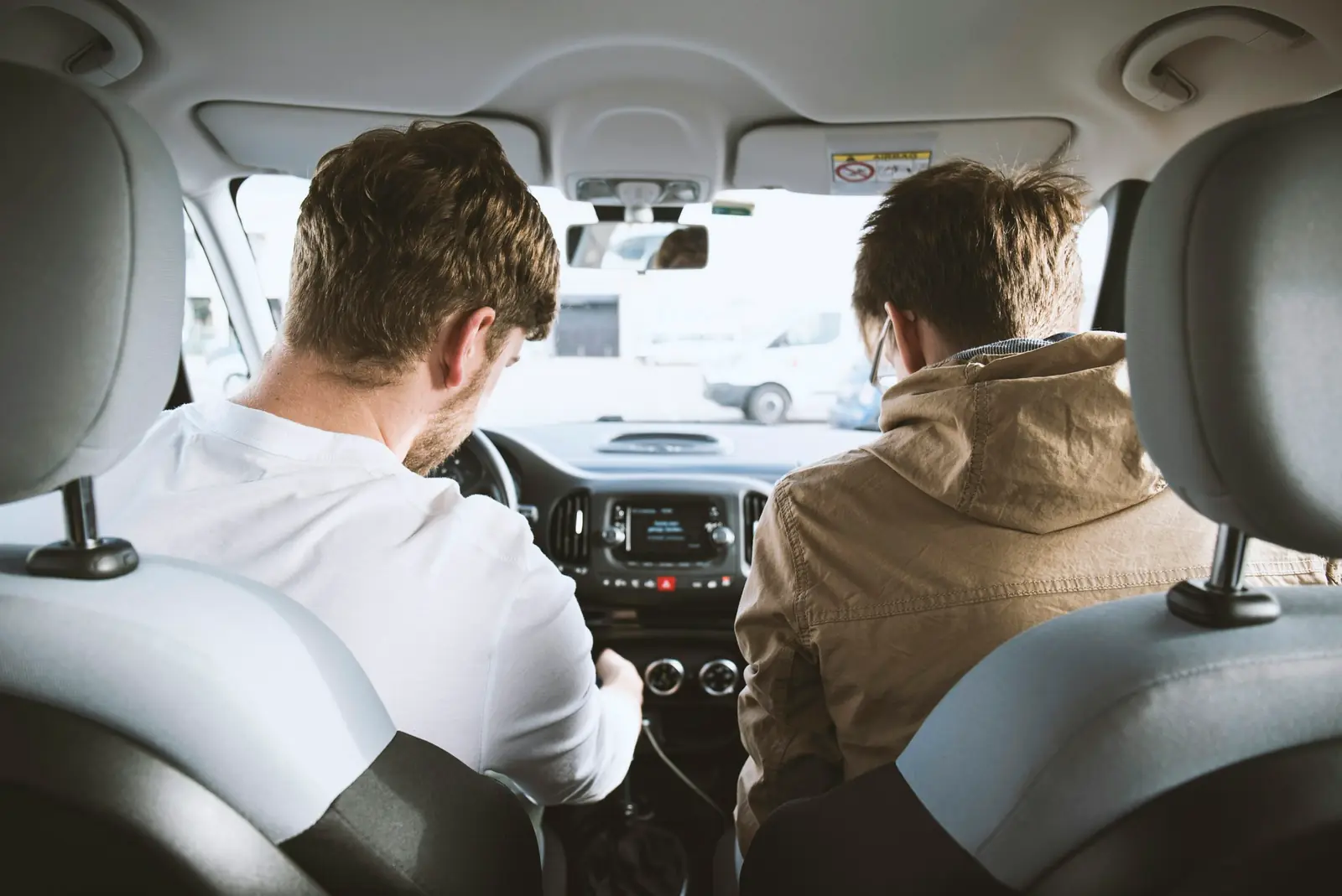 A driver and a passenger side by side in the front seats of the same car